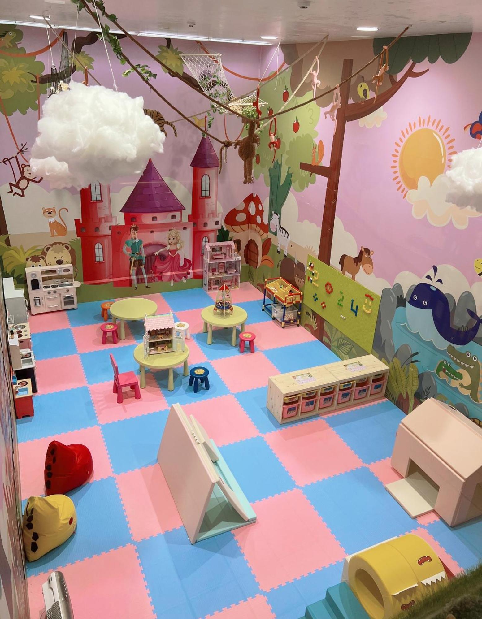 Evergreen Laurel Hotel - Тайчжун Экстерьер фото The photo shows a colorful playroom designed for children. It features a vibrant mural with a fairytale castle, trees, and playful animals on the walls. The floor is covered with interlocking foam tiles in pink and blue, providing a soft play surface