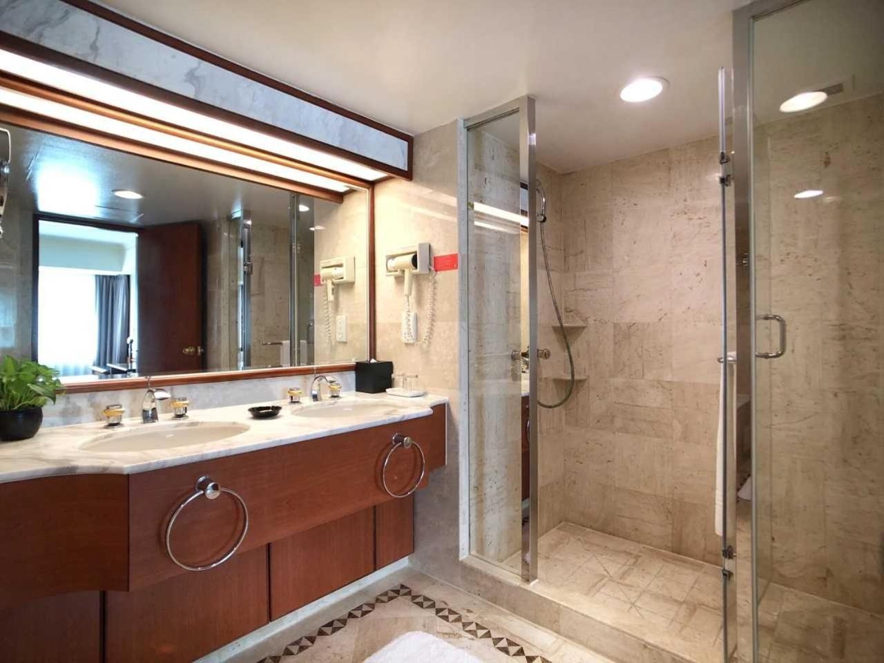 Evergreen Laurel Hotel - Тайчжун Экстерьер фото The photo depicts a modern bathroom featuring a double vanity sink with a marble countertop and wooden cabinetry. Above the sinks, there is a large mirror with integrated lighting. To one side, there is a shower enclosed in glass, showcasing a sleek 