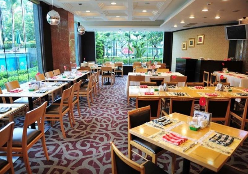 Evergreen Laurel Hotel - Тайчжун Экстерьер фото The photo shows an interior of a restaurant with a spacious layout. There are several wooden tables, each set with napkins and utensils. The floor has a decorative carpet, and large windows provide a view of greenery outside. The lighting is bright, 