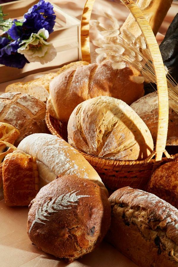 Evergreen Laurel Hotel - Тайчжун Экстерьер фото The photo shows a variety of freshly baked bread arranged in a woven basket. There are different types of bread, including round loaves, baguettes, and crusty rolls, showcasing a range of colors and textures. Some loaves have distinctive patterns or 