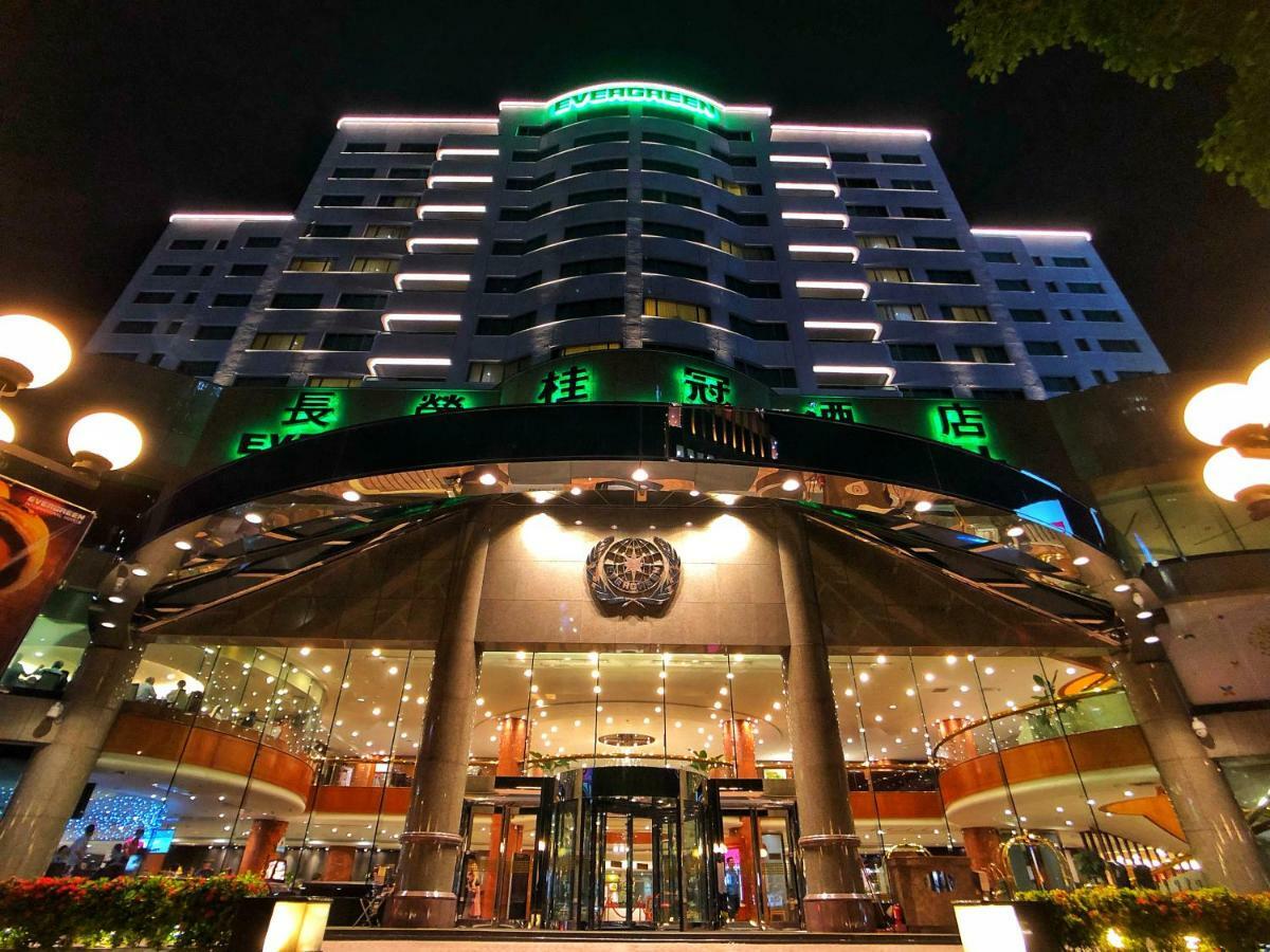 Evergreen Laurel Hotel - Тайчжун Экстерьер фото The photo shows a modern building at night, featuring a grand entrance with illuminated signage. The structure has multiple stories with a sleek design, adorned with green lighting that highlights its architectural features. The entrance is spacious 