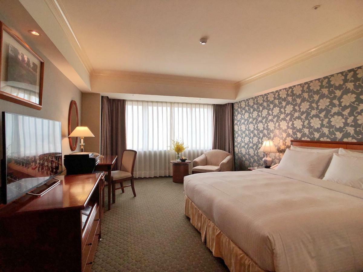 Evergreen Laurel Hotel - Тайчжун Экстерьер фото The photo shows a hotel room with a spacious layout. It features a large bed with white bedding, bedside lamps, and a decorative headboard. There is a comfortable seating area with an armchair and small table. A desk is present, complete with a lamp 