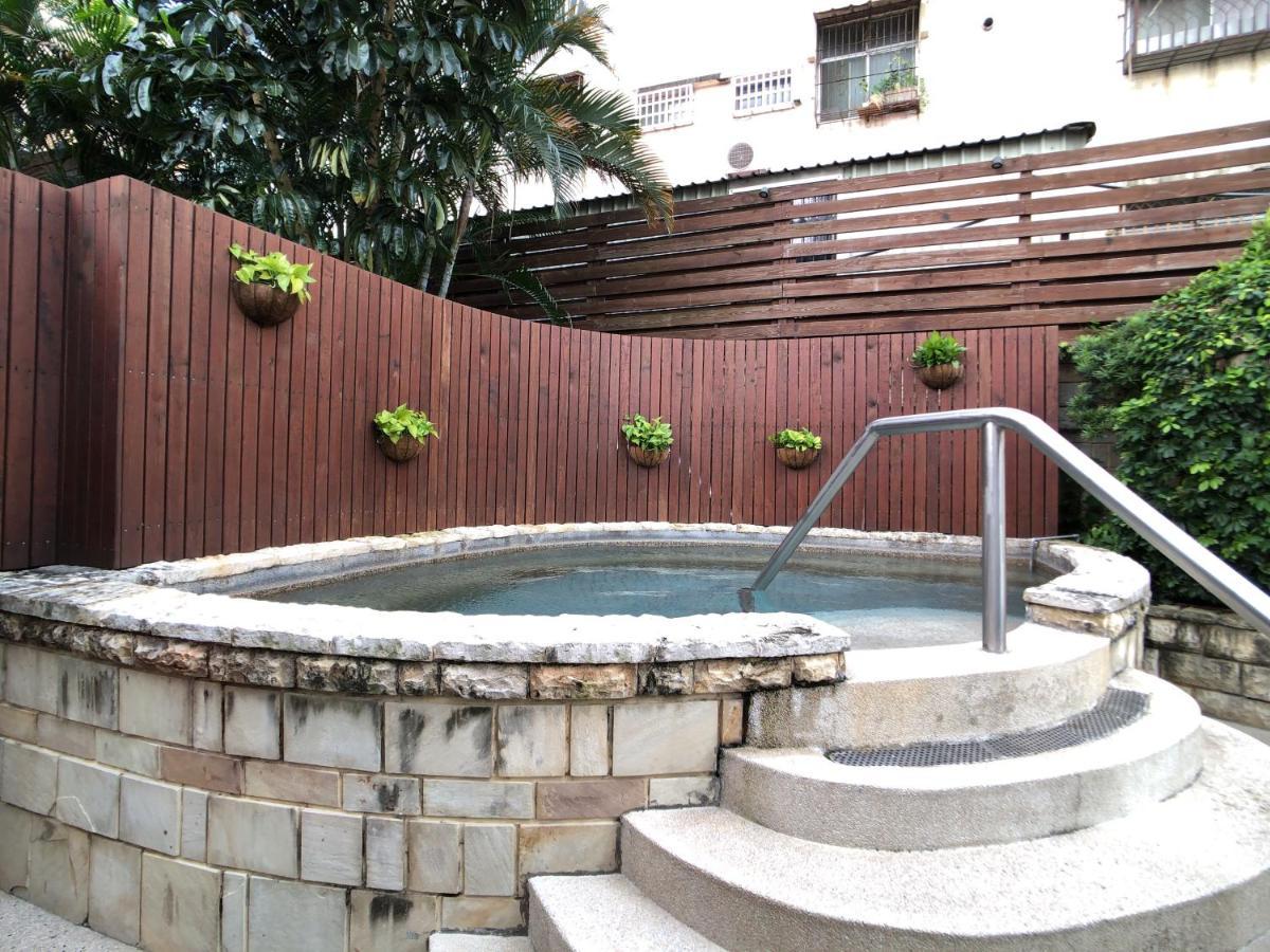 Evergreen Laurel Hotel - Тайчжун Экстерьер фото The photo shows a small outdoor hot tub or spa area. It's surrounded by a wooden fence, with several planters containing greenery attached to the wall. The hot tub is round, with a stone border, and there are steps leading up to it with a stainless s